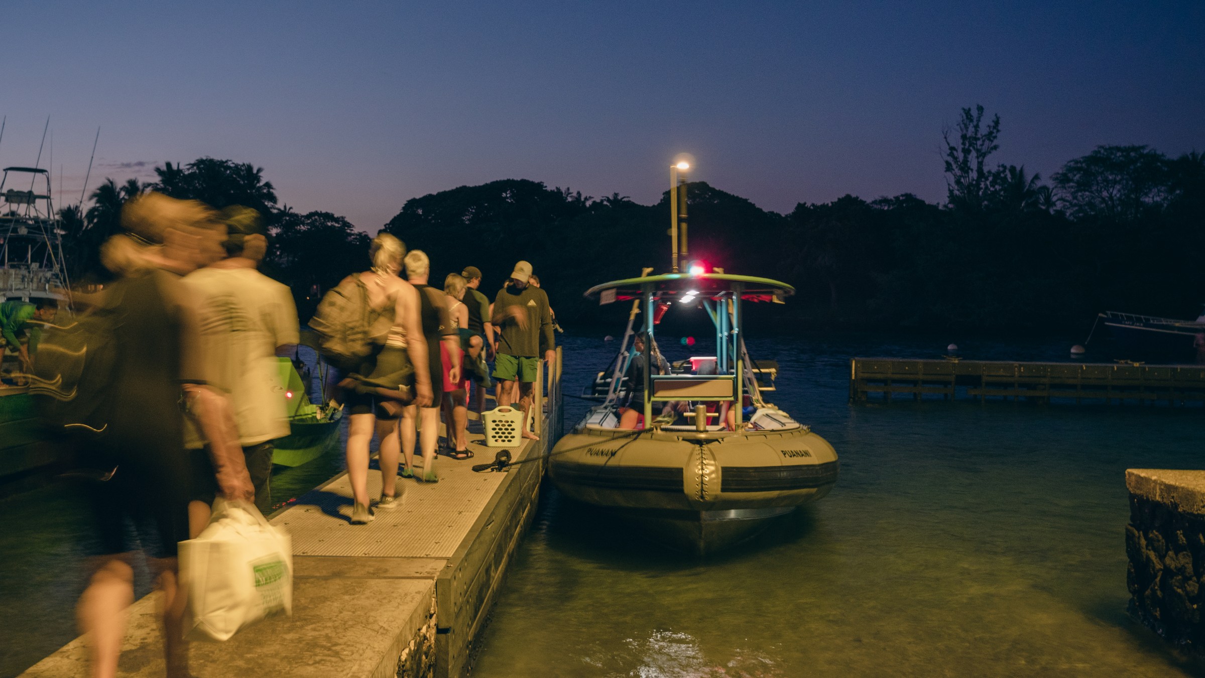 People boarding a small boat at a dock during twilight.