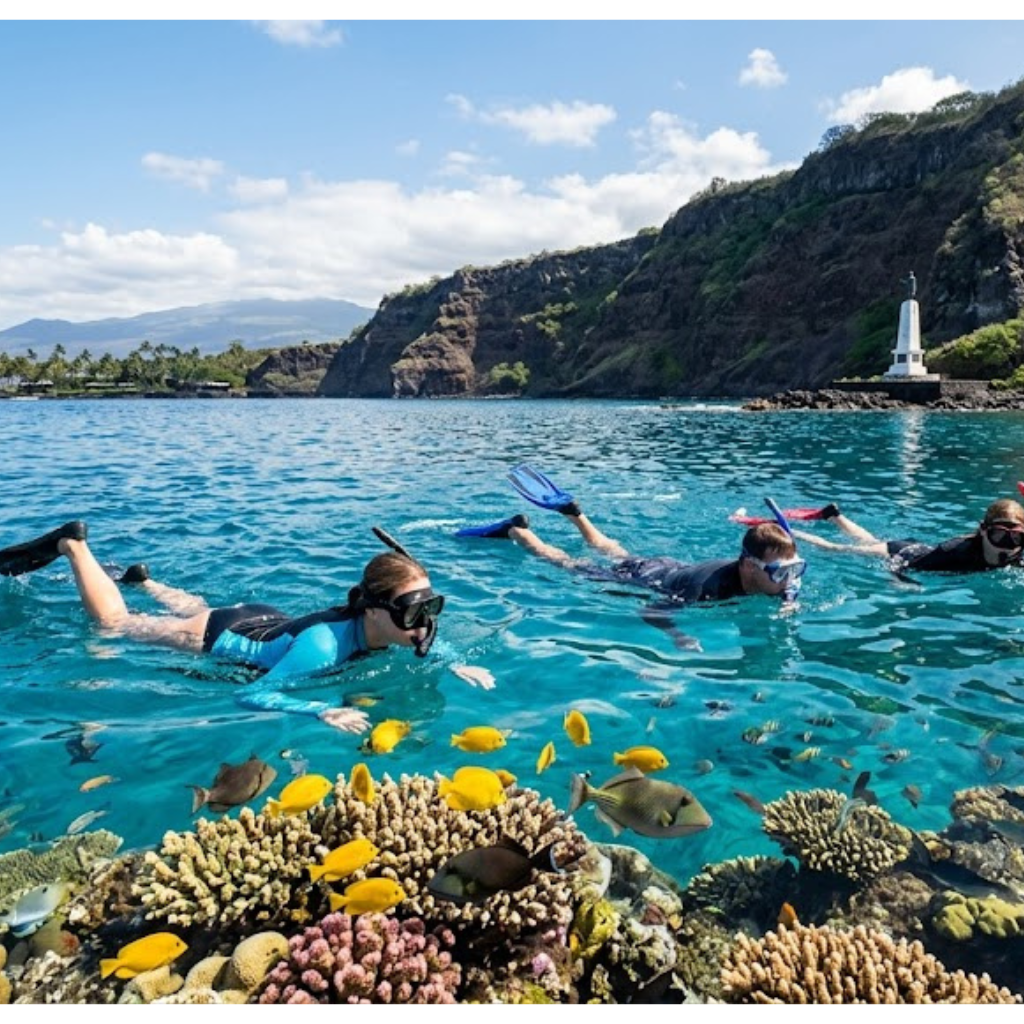 Three snorkelers swim over coral reef in clear blue water.