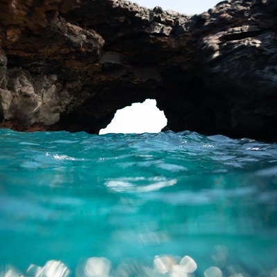 Ocean cave with turquoise water and rocky arch above.